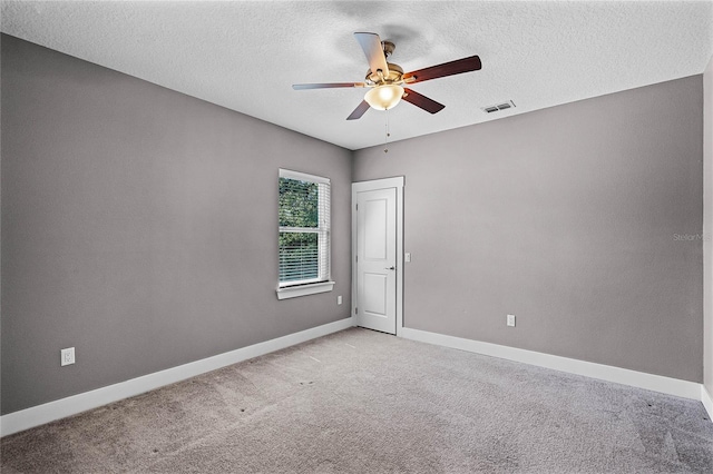 spare room with visible vents, a textured ceiling, baseboards, light colored carpet, and ceiling fan