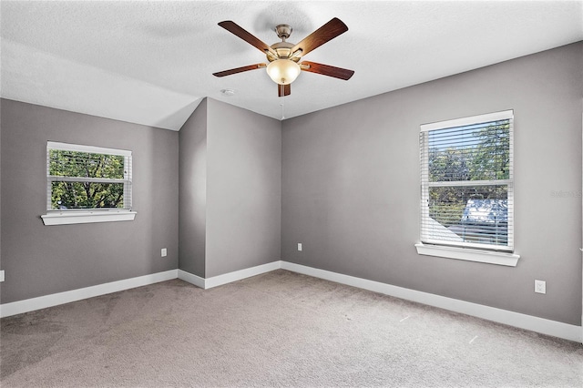 unfurnished room featuring a ceiling fan, light colored carpet, baseboards, and a textured ceiling