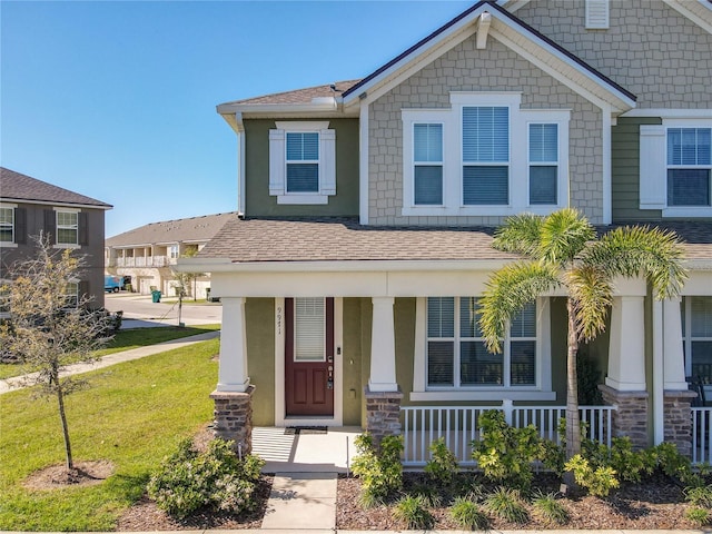 craftsman house featuring a shingled roof, covered porch, and a front lawn