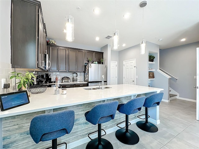 kitchen with visible vents, appliances with stainless steel finishes, light countertops, dark brown cabinets, and a sink