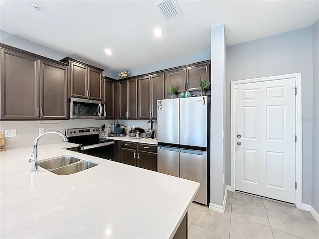 kitchen with a sink, visible vents, dark brown cabinets, appliances with stainless steel finishes, and light countertops