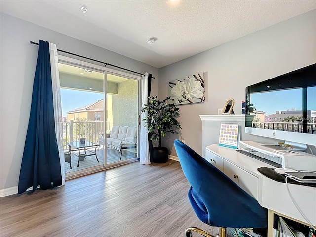 office area with a textured ceiling, baseboards, and light wood-style floors