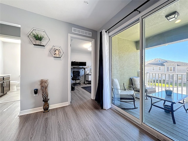 corridor with wood finished floors, visible vents, and baseboards