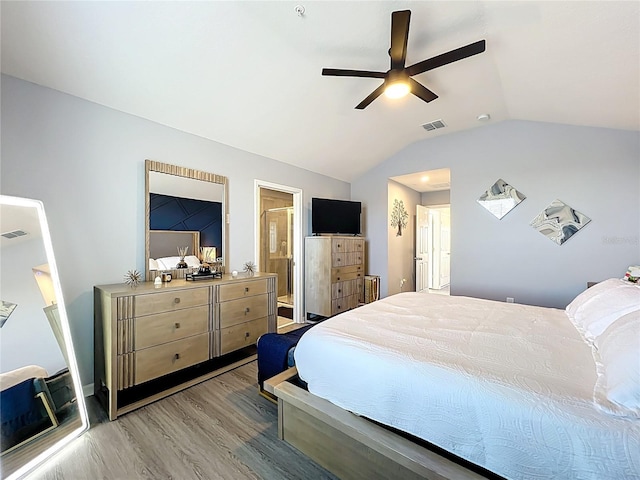 bedroom featuring light wood finished floors, lofted ceiling, visible vents, a ceiling fan, and ensuite bath