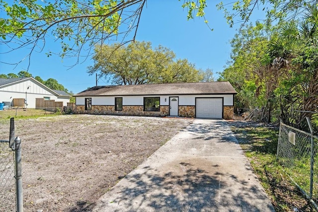 view of front of house with stone siding, concrete driveway, an attached garage, and fence