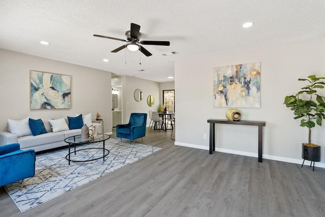 living area featuring visible vents, a textured ceiling, baseboards, and wood finished floors