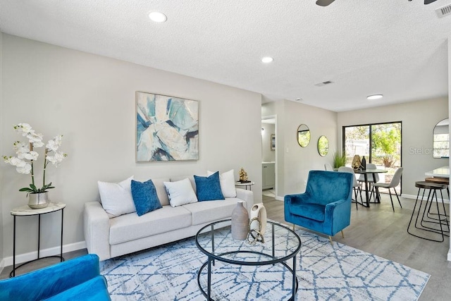 living area featuring visible vents, a textured ceiling, and wood finished floors