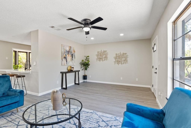 living area featuring recessed lighting, visible vents, a textured ceiling, wood finished floors, and baseboards