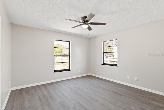 unfurnished room with dark wood finished floors, a wealth of natural light, and baseboards