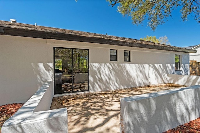 rear view of house featuring stucco siding