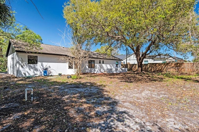 rear view of property featuring fence and stucco siding