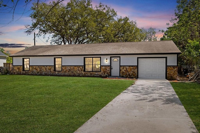 view of front of home featuring a garage, stone siding, a front yard, and driveway