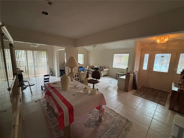 interior space featuring vaulted ceiling, light tile patterned floors, and a textured ceiling