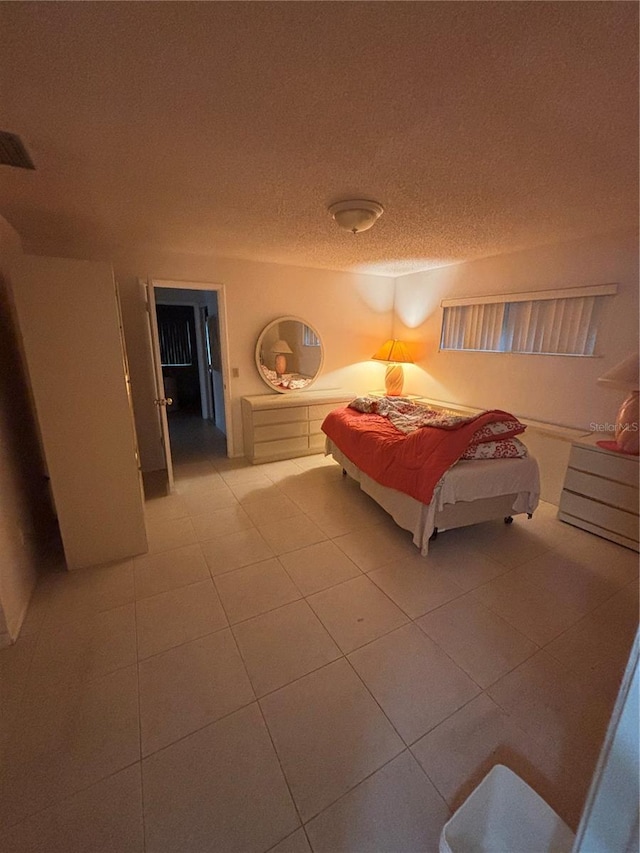 bedroom featuring visible vents, light tile patterned flooring, and a textured ceiling