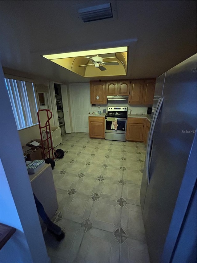 kitchen featuring under cabinet range hood, stainless steel appliances, visible vents, light countertops, and a raised ceiling