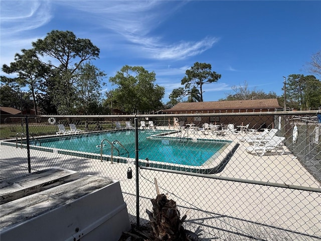 pool with a patio area and fence