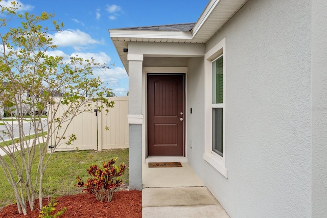 entrance to property with fence and stucco siding