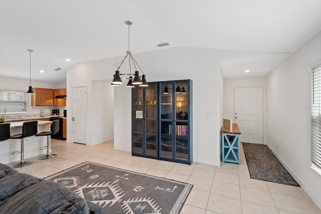 living area with light tile patterned floors, lofted ceiling, visible vents, and baseboards