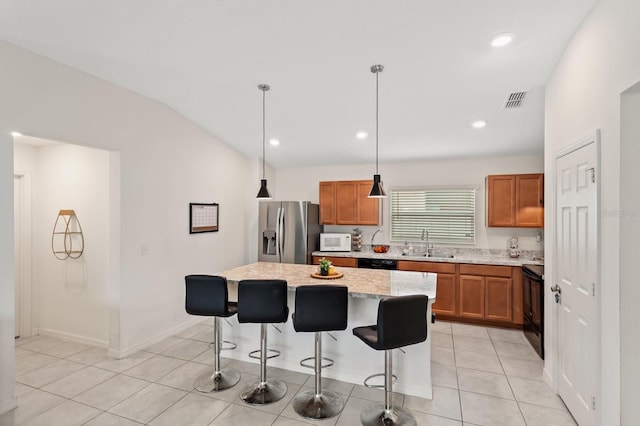 kitchen featuring a breakfast bar area, visible vents, light tile patterned flooring, a sink, and black appliances