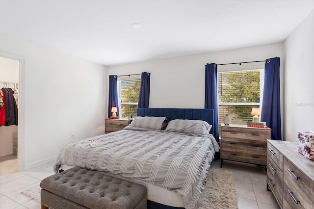 bedroom featuring a walk in closet, a closet, multiple windows, and light tile patterned flooring