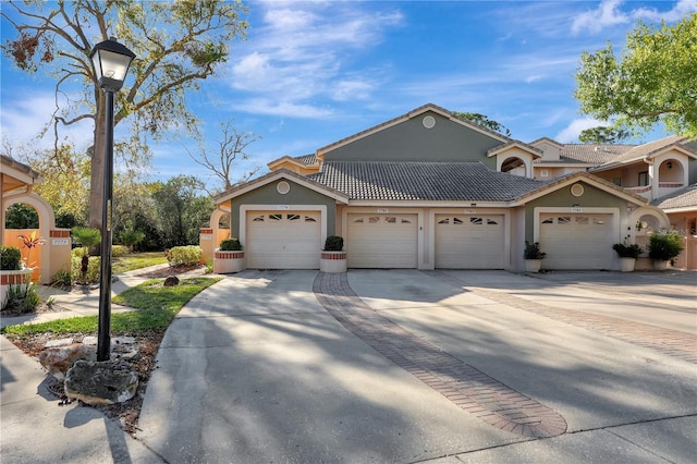 view of front of home featuring a tiled roof, a garage, driveway, and stucco siding