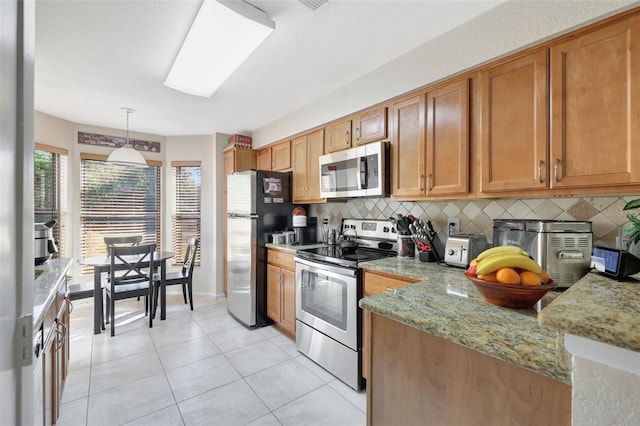 kitchen featuring tasteful backsplash, light stone countertops, light tile patterned floors, brown cabinetry, and stainless steel appliances