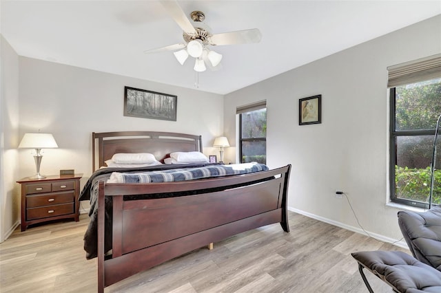 bedroom featuring multiple windows, light wood-style floors, and baseboards