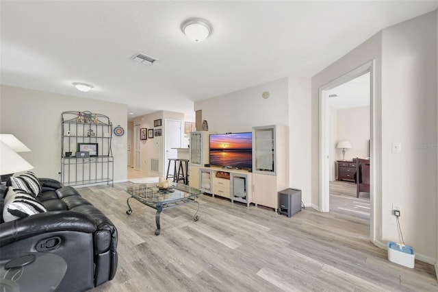 living room featuring light wood-style flooring, baseboards, and visible vents