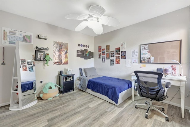 bedroom with a ceiling fan, wood finished floors, and baseboards