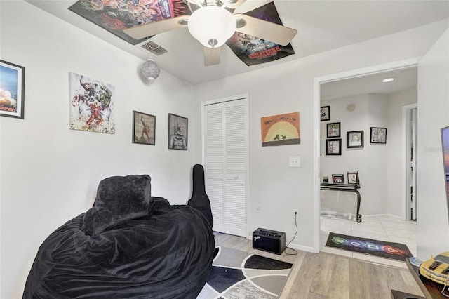 living area with visible vents, baseboards, a ceiling fan, and wood finished floors