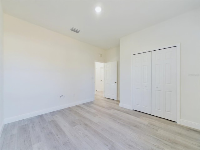 unfurnished bedroom with a closet, visible vents, light wood finished floors, and baseboards