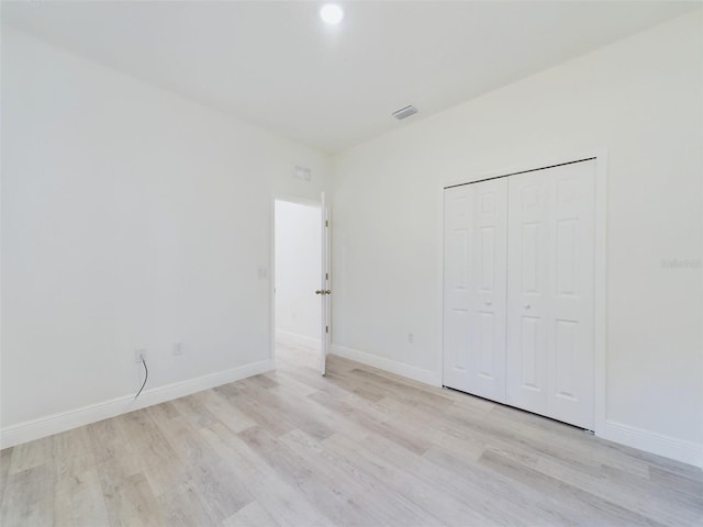 unfurnished bedroom with light wood-style floors, a closet, visible vents, and baseboards