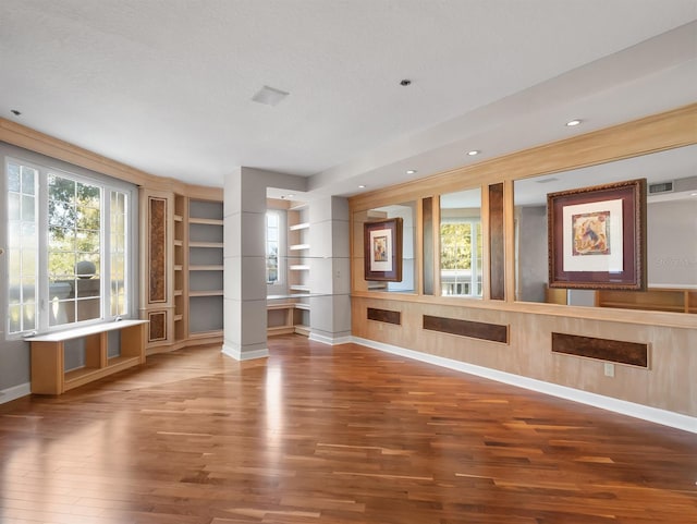 interior space with built in shelves, a wealth of natural light, baseboards, and wood finished floors