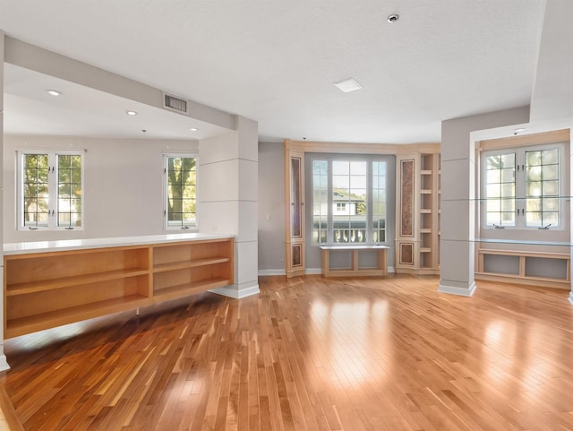 unfurnished living room with light wood-style floors, visible vents, and baseboards