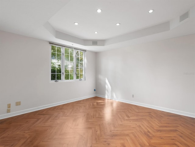 unfurnished room with recessed lighting, a raised ceiling, visible vents, and baseboards