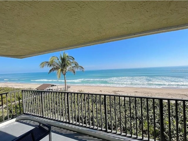 balcony featuring a water view and a beach view