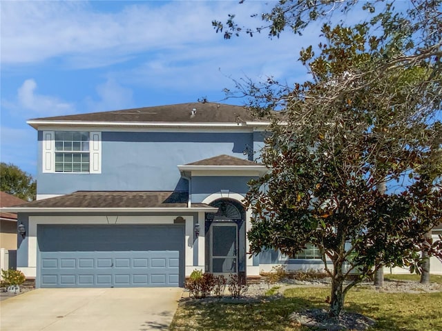 traditional-style house featuring a garage, concrete driveway, and stucco siding