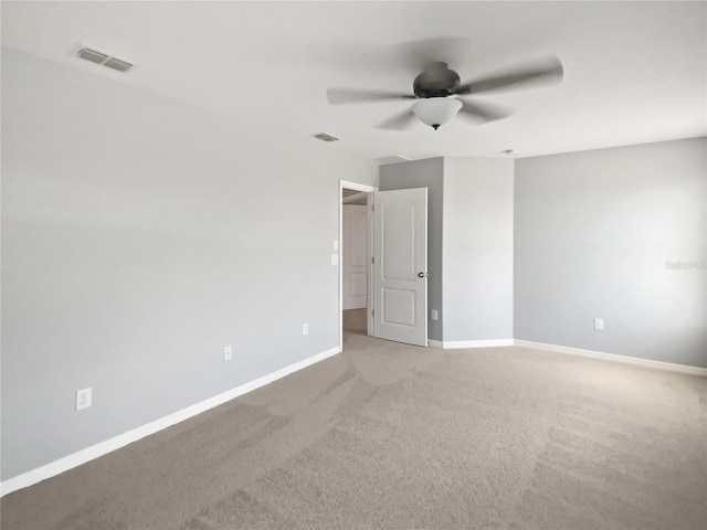 empty room featuring a ceiling fan, carpet flooring, visible vents, and baseboards