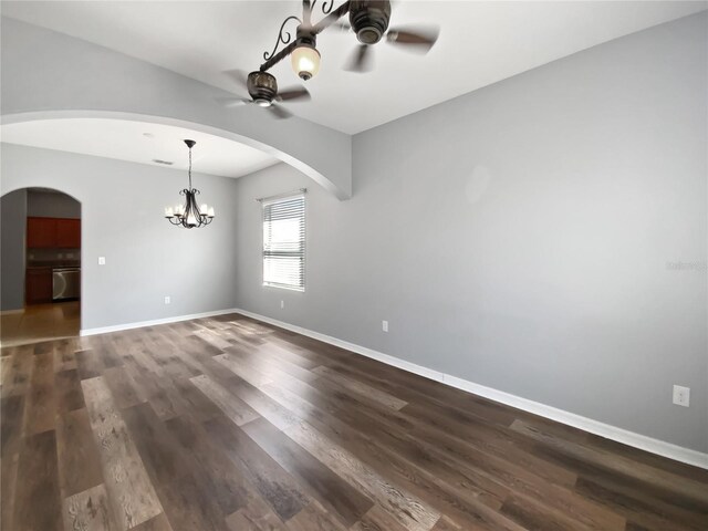 empty room featuring ceiling fan with notable chandelier, dark wood-style flooring, visible vents, and baseboards