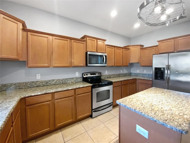 kitchen featuring light tile patterned floors, appliances with stainless steel finishes, brown cabinets, light stone counters, and recessed lighting