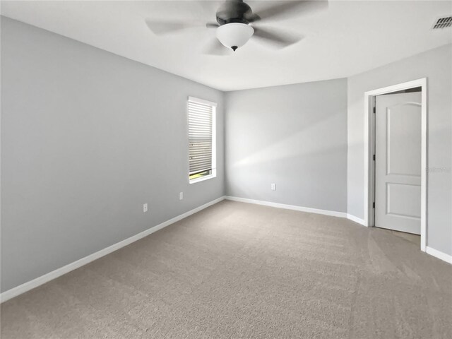 empty room with carpet, baseboards, visible vents, and a ceiling fan