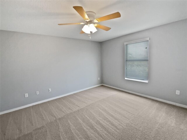 carpeted empty room with a ceiling fan and baseboards