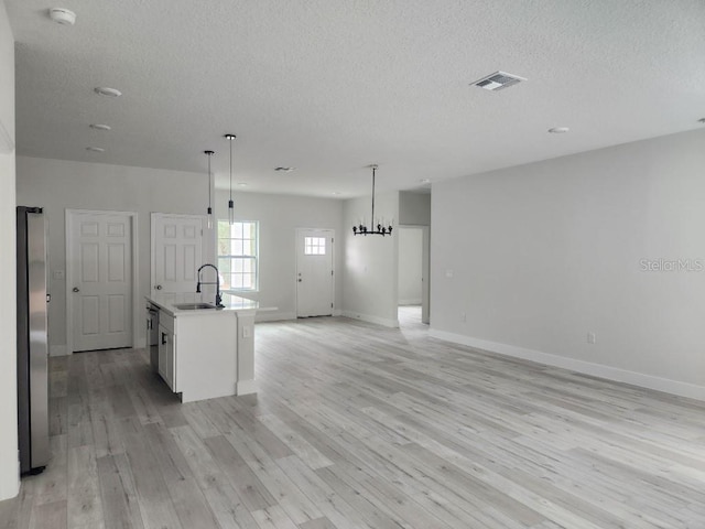 kitchen featuring visible vents, open floor plan, freestanding refrigerator, light wood-type flooring, and a sink