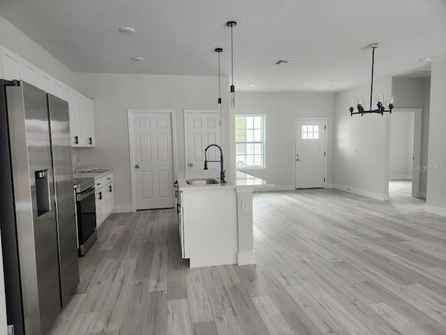 kitchen with stainless steel appliances, a sink, white cabinets, light countertops, and light wood finished floors