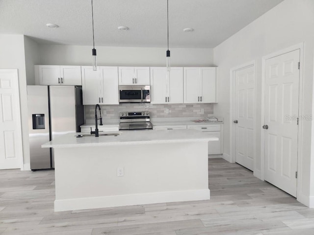 kitchen featuring a sink, white cabinetry, light countertops, appliances with stainless steel finishes, and a center island with sink