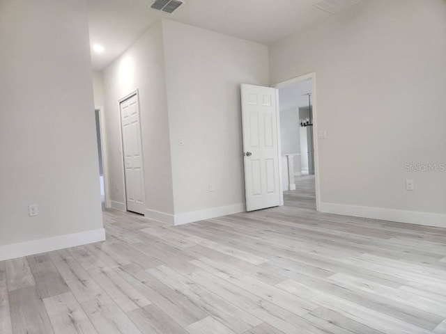 empty room featuring light wood-type flooring, visible vents, and baseboards