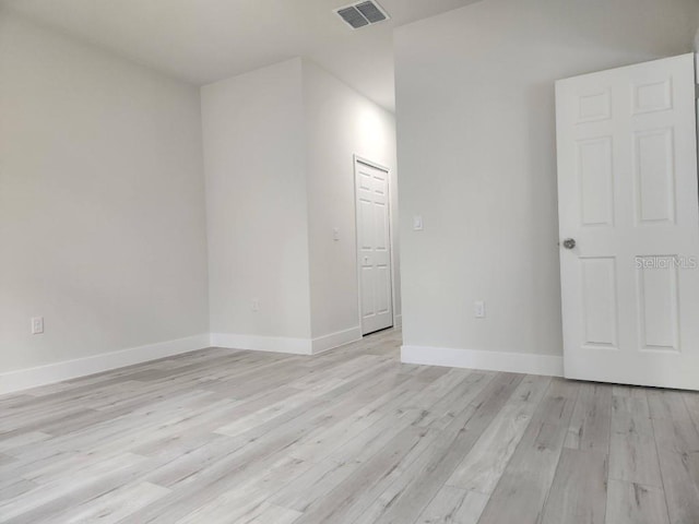 empty room with light wood-style flooring, visible vents, and baseboards