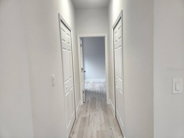 hall with light wood-type flooring and baseboards