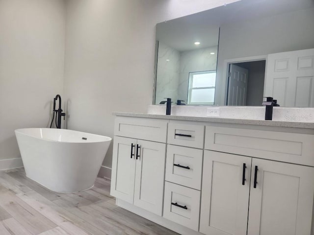 full bath with a walk in shower, double vanity, a soaking tub, and wood finished floors