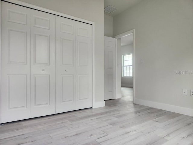 unfurnished bedroom with a closet, light wood-type flooring, visible vents, and baseboards